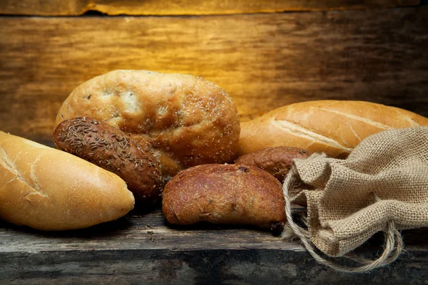 Pan fresco y trigo en la madera — Foto de Stock