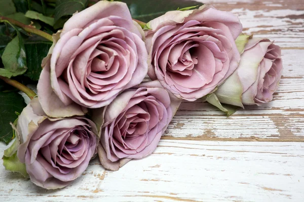 Violette Rosen auf hölzerner Oberfläche — Stockfoto