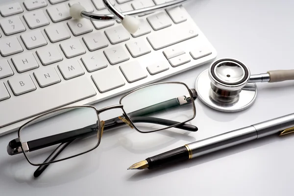 Stetoskop på ett bord med tangentbord och glasögon — Stockfoto