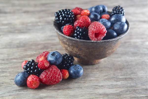 Assorted berries in bowl on wood — Stock Photo, Image