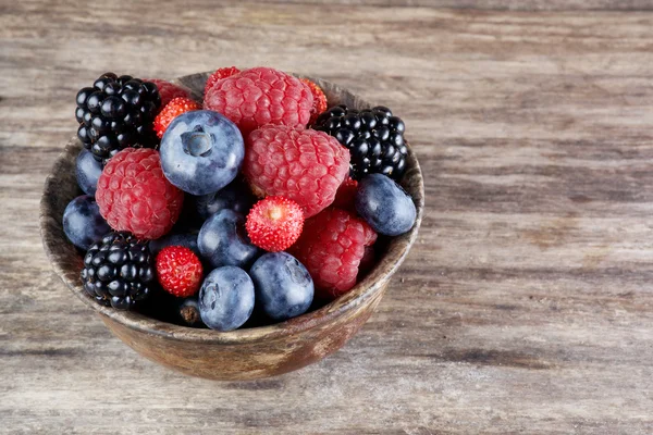 Assorted berries in bowl on wood — Stock Photo, Image