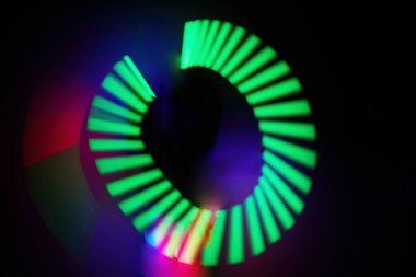 Karanlık bir uzayda canlı yeşil ve mavi ışık huzmelerinin dinamik sarmalı.