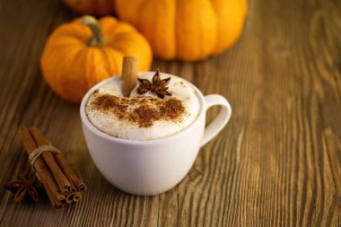 Ahşap bir masada tarçınlı, yıldız anason ve balkabaklı sıcacık bir sonbahar lattesi..