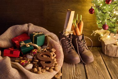 Noel ağacının yanında hediyeler, şekerler ve ayakkabılarla neşeli Sinterklaas sahnesi.