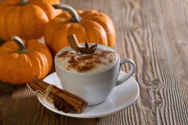 Tarçın çubukları, yıldız anason ve ahşap bir masa üzerinde balkabağı kokulu balkabağı lattesi..