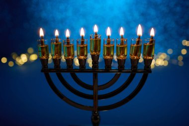 Işıklı bir menora karşı canlı mavi, şenlikli bir arkaplan.