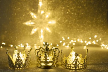 Karanlık, zarif bir atmosferde parıldayan peri ışıkları olan üç altın taç..