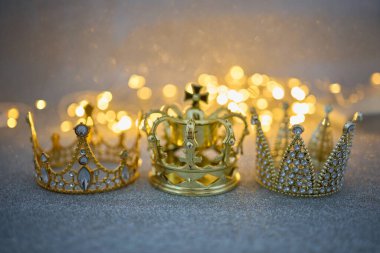 Parlak bir arka planda Bokeh ışıkları ile zenginlik ve güç gösteren üç altın taç.