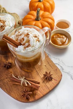 Krem şanti ve tarçınlı balkabağı aromalı latte, ahşap bir tahtada servis edilir.