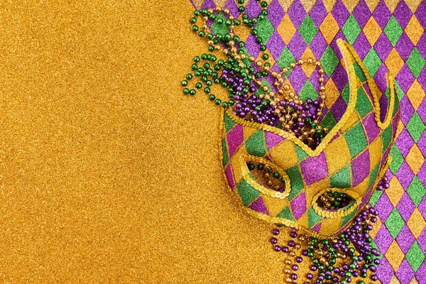 Mardi Gras maskesi. Elmas desenli pırıl pırıl altın bir yüzey üzerinde duran renkli boncuklar.