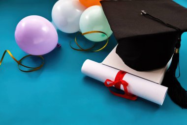 Mezuniyet şapkası, sarılı diploma ve akademik başarıyı kutlayan renkli balonlar.