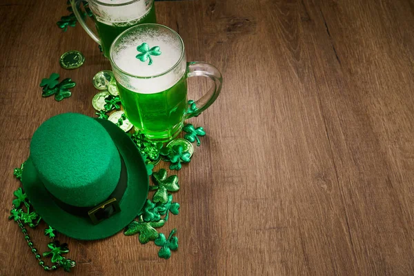 Yeşil bira bardakları ve Aziz Patrick Günü için ahşap arka plan süsleyen bir cüce şapka.