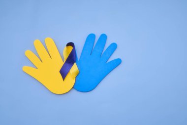 Sarı ve mavi kurdeleli kağıt eller aşağı sendromu sembolize ediyor.