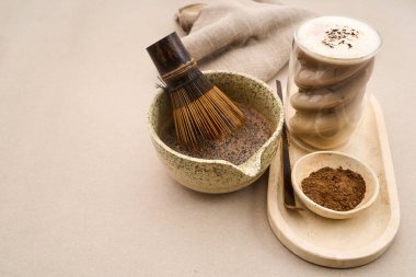 Kakao tozu, köpüklü lattenin yanında bambu çırpıcısıyla bir kâsede karışıyor.