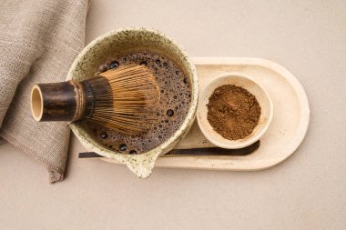Bambu chasen, çay tozuyla el yapımı seramik kasede Houjicha çayı çırpıyor.