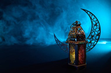 Süslü Arap metal feneri hilal arkaplanlı dumanlı atmosferi aydınlatıyor.