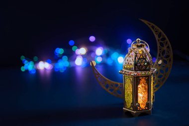 Süslü altın fener ve hilal renkli bokeh ışıklarıyla neşeli bir atmosfer yaratır.