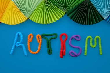 Kelime otizmi, kağıt yelpazeli mavi arka planda renkli duyusal oyuncaklardan oluşur.