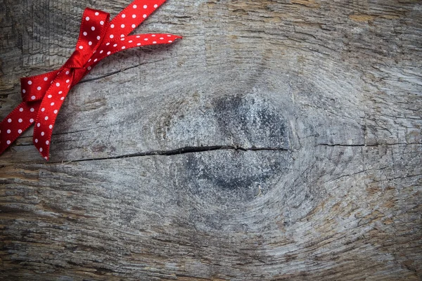 Trä bakgrund med röd och vit rutig rosett — Stockfoto