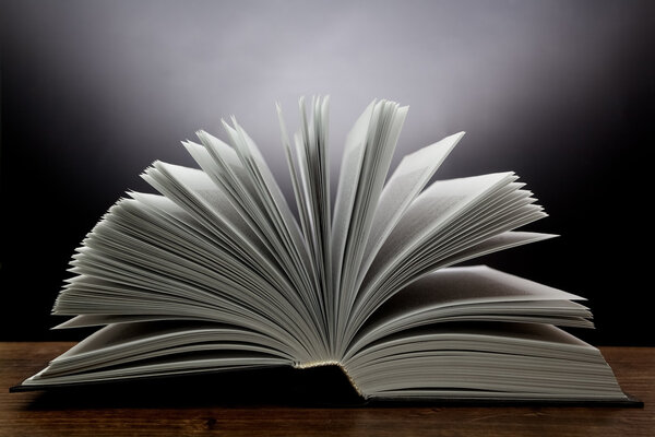 Старая открытая книга со светом на темном фоне
