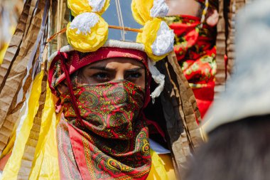 Puebla, Meksika 28 Eylül 2025: Huey Atlixcayotl festivalinde yerel kültürü temsil eden kırmızı ve altın desenli bir yüz eşarbı takan geleneksel giyinmiş bir dansçının yakın plan portresi.