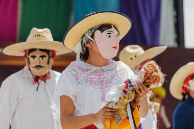 Puebla, Meksika 28 Eylül 2025: Kültürel bir kutlamaya katılan insan maskeli, hasır şapkalı ve geleneksel beyaz kostümlü dansçıların yakın çekimi