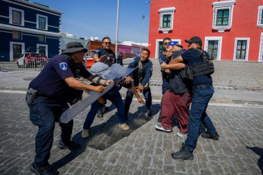 Puebla, Mxico; 11-15-25: Puebla, Meksika 'da bir koloni caddesinde şapka ve Meksika bayrağı taşıyan büyük bir protestocu kalabalığının yüksek açılı görüntüsü.