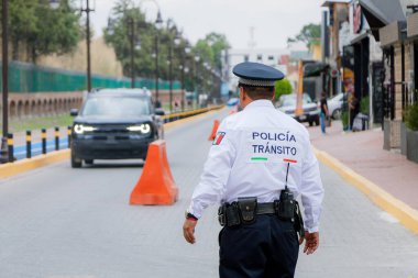 Bir trafik polisinin Meksika 'da bir caddede turuncu külahlı araçların akışını düzenleyen görüntüsü..