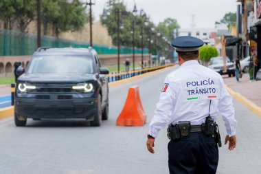 Bir trafik polisinin Meksika 'da bir caddede turuncu külahlı araçların akışını düzenleyen görüntüsü..