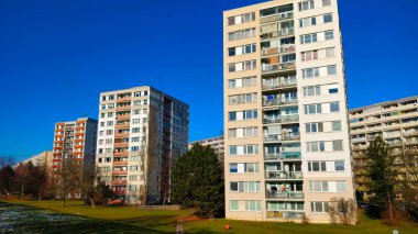 Biri arka planda olmak üzere Prag yerleşim bölgesinde üç büyük apartman bloğu bulunmaktadır. Ocak ayının soğuk bir günü ve gökyüzünün güzel koyu mavi bir rengi var. Binaların tüm yüzeyi güneş ışığıyla kaplı..