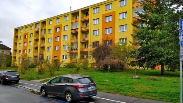 Prag 'daki konut alanındaki tipik bir apartman dairesi. Ön cephe sarı ve turuncu. Binanın önünde biraz çimen var ve hava bulutlu..