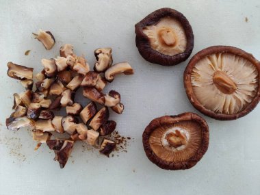 Beyaz arka planda Shiitake mantarları. Biri parçalara ayrılmış ve üçü bir bütün olmuş..