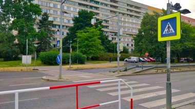 Prag, Çek Cumhuriyeti - 15 Haziran 2021: Zebra, yolun diğer tarafındaki eski apartman bloklarıyla son derece yansıtıcı yol tabelasıyla karşıya geçiyor. Ön planda kırmızı-beyaz metal parmaklıklar var..