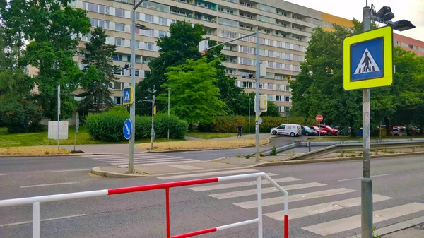 Prag, Çek Cumhuriyeti - 15 Haziran 2021: Zebra, yolun diğer tarafındaki eski apartman bloklarıyla son derece yansıtıcı yol tabelasıyla karşıya geçiyor. Ön planda kırmızı-beyaz metal parmaklıklar var..