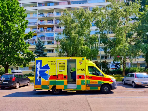 Prag, Çek Cumhuriyeti - 19 Haziran 2021: Ambulans arabası arka planda ağaçlar ve apartman bulunan bir yerleşim alanındaki yola park edildi.