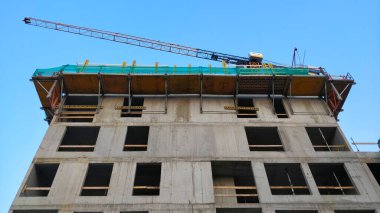 Prag, Çek Cumhuriyeti - 23 Temmuz 2021: Tamamlanmamış yüksek katlı konut inşaatı aşağıdan gökyüzüne kadar görülmekte ve vinç üzerinde çalışmaktadır.