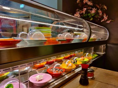 Kapalı bir suşi restoranı işletiyor ve iki kat yemek servis ediliyor. Tabaklar çok renkli..