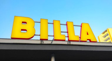 Prag, Çek Cumhuriyeti - 8 Eylül 2021: Süpermarket zinciri Billa 'nın sarı logosu, arka planda mavi gökyüzü olan binanın çatısına sabitlendi.