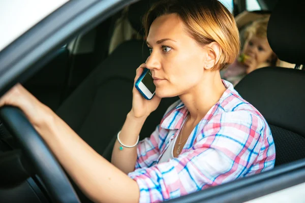 Busy mother speaks on her smartphone — Stock Photo, Image