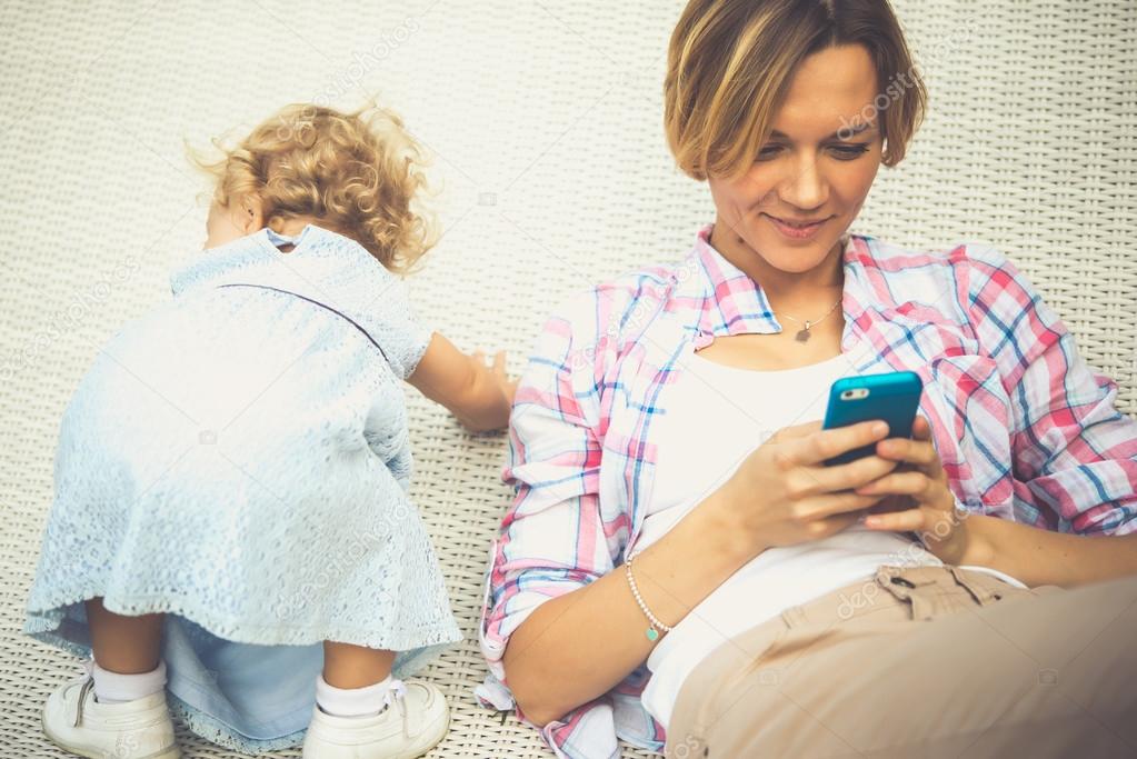 удаленная работа. мама с телефоном в руках. мама с ребенком с телефоном. телефон для мамы. современная мама с ребенком.