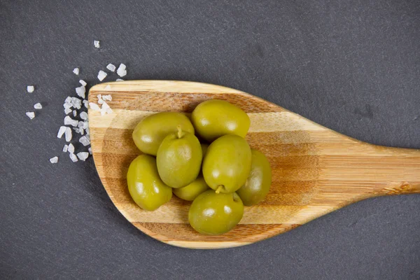 Groene olijven op houten lepel — Stockfoto