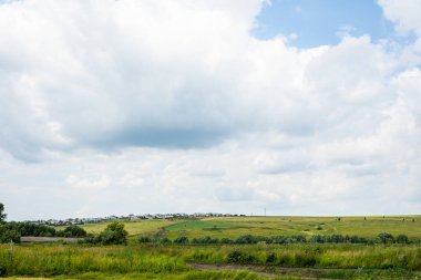 Güzel kırsal alan, yeşil bir tepenin üzerindeki köy ve bulutlu mavi gökyüzü. Doğa yaşam geçmişi