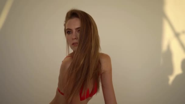 Дівчина в червоній позі білизни на білій стіні — стокове відео