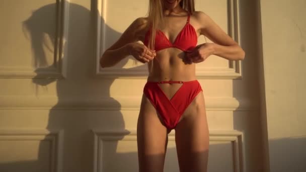 Tyttö punaisissa alusvaatteissa poseeraa valkoista seinää vasten — kuvapankkivideo