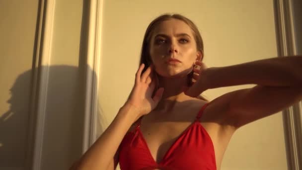 Ein Mädchen in roter Unterwäsche posiert vor einer weißen Wand — Stockvideo