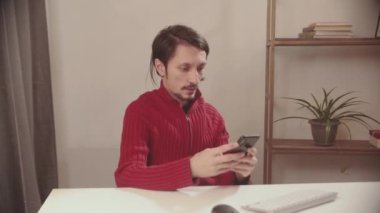 Adam elinde bir cep telefonu tutuyor ve gülümsüyor.