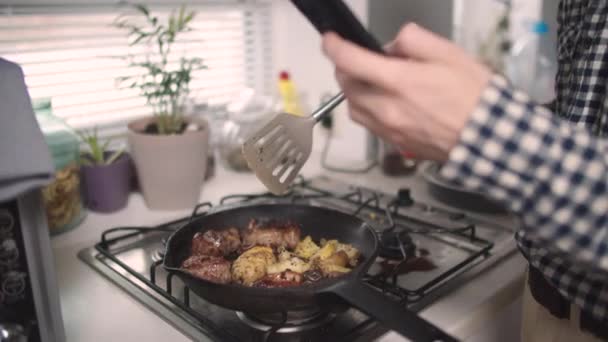 Um homem com um telefone na mão prepara comida em uma frigideira — Vídeo de Stock