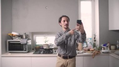 Adam yemek pişiriyor ve video iletişimiyle konuşuyor.
