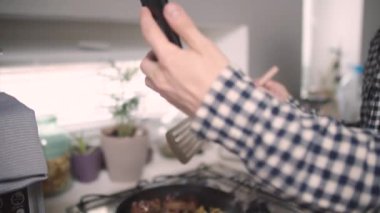 Adam yemek pişiriyor ve video iletişimiyle konuşuyor.