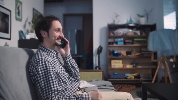 O cara senta-se e alegremente fala ao telefone — Vídeo de Stock